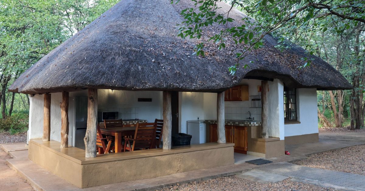 A spacious, traditional thatched chalet at Bateleur Bushveld Camp, set amongst established trees in a remote area of the park.