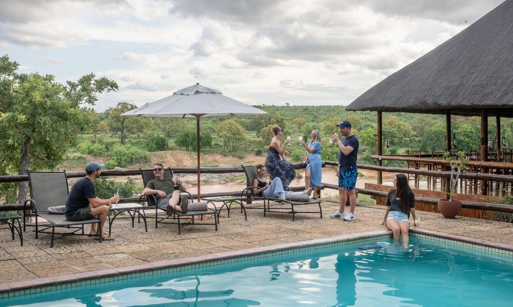 swimming pool at nyati safari lodge with guests enjoying the view of the river