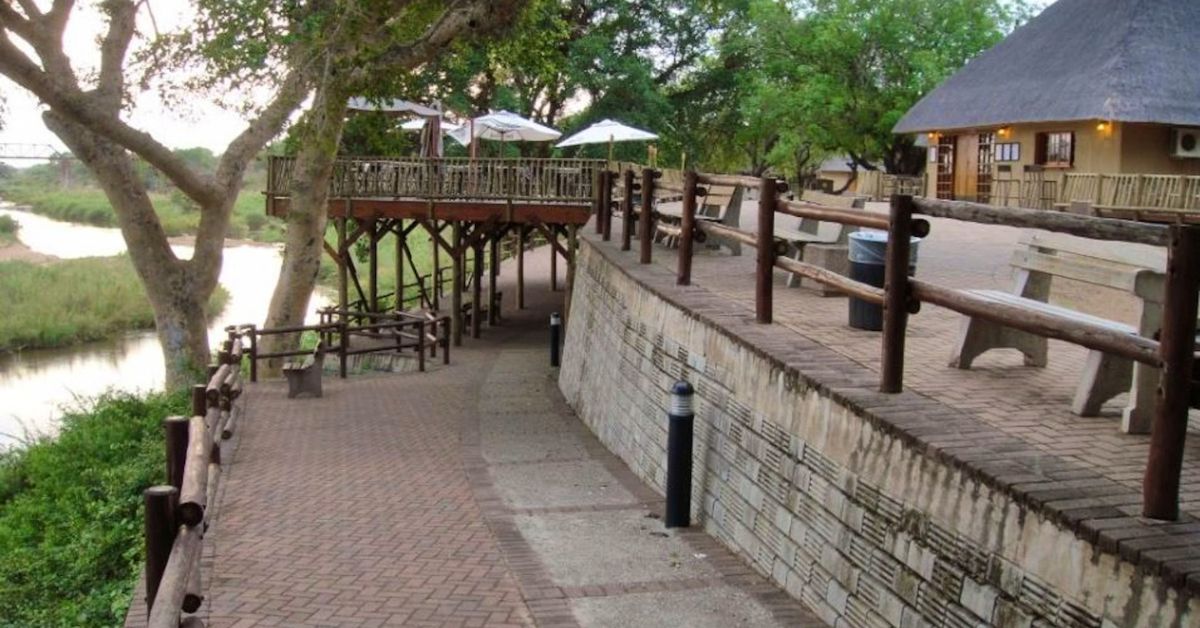 A wooden walkway path winding through the grounds at Skukuza Rest Camp.