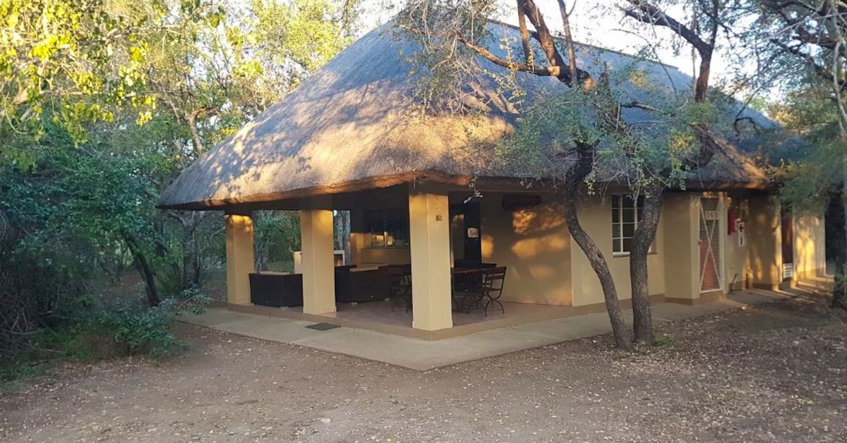A cozy thatched bungalow at Talamati Bushveld Camp with natural landscaping and a shaded porch.